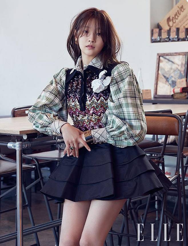 퍼프 소매의 체크 셔츠와 레인보 스팽글 장식의 베스트, 티어드 스커트, 레더 브레이슬렛, 레이어드한 B 블라썸 파인 주얼리 링, 골드 이어링은 모두 Louis Vuitton.