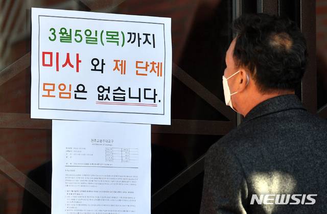 성당 입구에 붙어 있는 미사중단 안내문을 한 교우가 바라보고 있다. (뉴시스 DB)