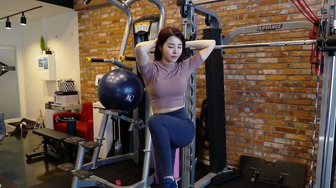 Knee-up twist -- works abs and back muscles (Park Su-bin / The Korea Herald)