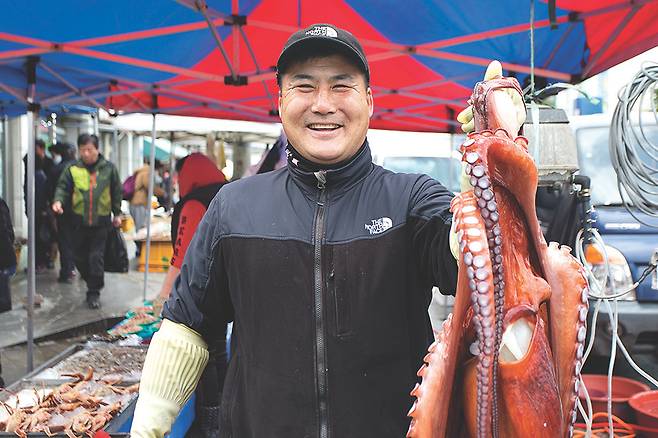 문어를 들어보이며 사람 좋은 웃음을 짓는 북평민속시장 어물전의 김석호씨.