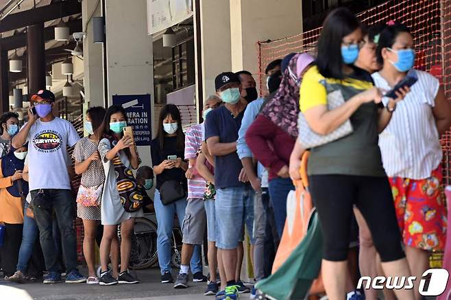 싱가포르의 한 식료품 시장 앞에서 마스크를 쓴 사람들이 줄을 서서 입장을 기다리고 있다. © AFP=뉴스1