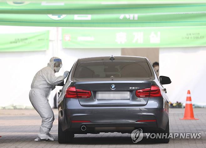 '자세를 낮추고' (서울=연합뉴스) 이지은 기자 = 7일 오전 서울 송파구 잠실종합운동장 주경기장에 설치된 신종 코로나바이러스(코로나19) 드라이브 스루 선별진료소에서 의료진이 검체 채취를 하고 있다. 2020.4.7 jieunlee@yna.co.kr