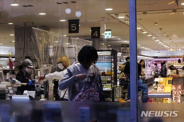[도쿄=AP/뉴시스]일본 도쿄에서 지난 2일 한 여성이 슈퍼마켓을 방문해 쇼핑을 한 후 짐을 챙기고 있다. 신종 코로나바이러스 감염증(코로나19) 예방을 위해 계산대에 설치된 비닐 커튼이 여성의 뒤로 보인다. 2020.05.04.