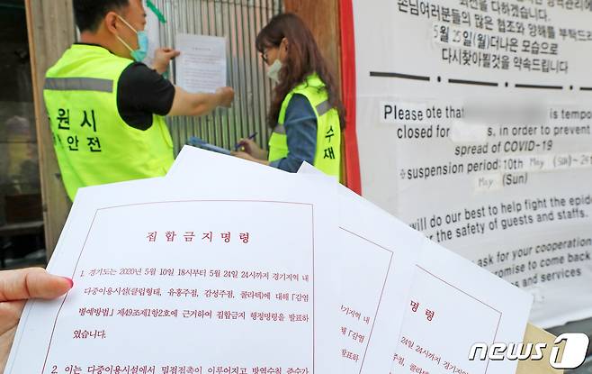 경기 수원시청 관계자들이 인계동의 한 감성주점 출입구에 신종 코로나바이러스 감염증(코로나19) 확산 방지를 위한 집합금지명령서를 부착하고 있다. 2020.5.11/뉴스1