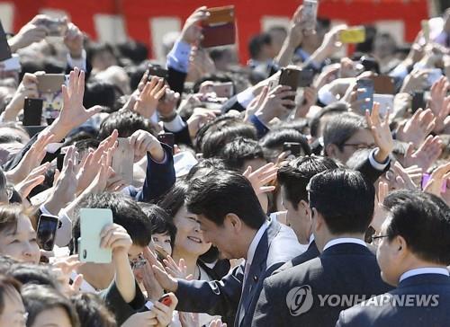 작년 4월 신주쿠교엔에서 열린 '벚꽃을 보는 모임' 행사에서 아베 신조 총리가 참가자들과 손을 마주치고 있다. [교도=연합뉴스 자료사진]