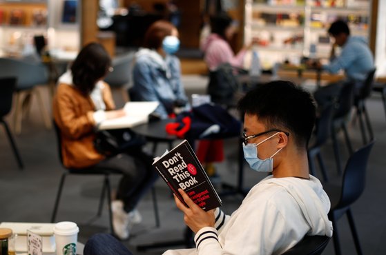 지난 4일 중국 베이징의 한 쇼핑몰에서 한 남성이 마스크를 쓴 채 책을 읽고 있다.[로이터=연합뉴스]