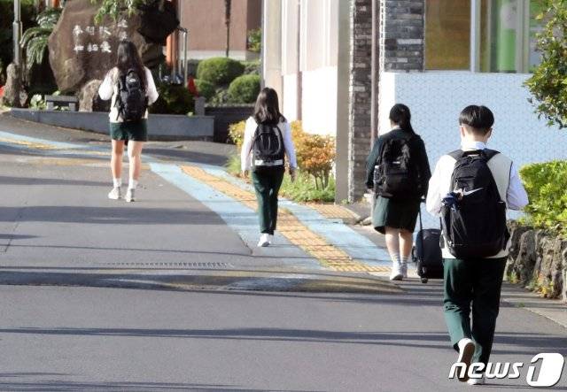 (제주=뉴스1) 신종코로나바이러스(코로나19) 확산으로 미뤄졌던 고3 등교가 시작된 20일 제주시 아라일동 제주여자고등학교에서 마스크를 쓴 학생들이 거리두기를 하며 학교 안으로 향하고 있다.2020.5.20/뉴스1