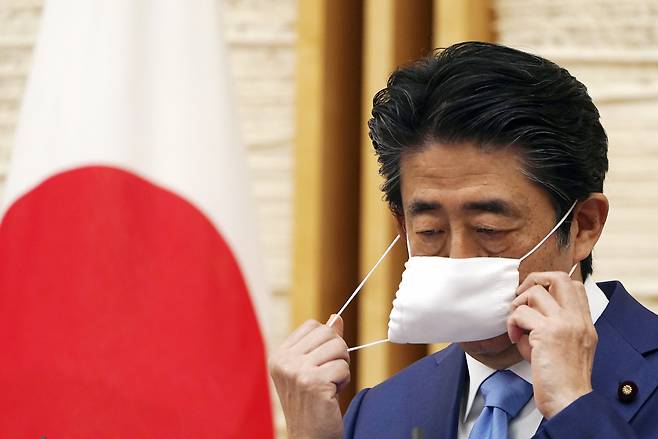 마스크를 벗는 아베 신조 일본 총리. [AP]