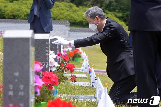 노태우 전 대통령 아들 노재헌씨가 29일 광주 북구 운정동 국립5·18민주묘지에서 헌화·분향을 한 뒤 묘역 앞에 무릎 꿇고 묘비를 어루만지고 있다. 노씨는 참배에 앞서 방명록에 '5·18 광주민주화운동 40주년을 기리며 대한민국 민주화의 씨앗이 된 고귀한 희생에 고개숙여 감사드립니다'라고 적었다. 또 '제13대 대통령 노태우-5·18민주영령을 추모합니다'라고 적힌 조화를 헌화했다. 20205.29 /뉴스1 © News1 한산 기자