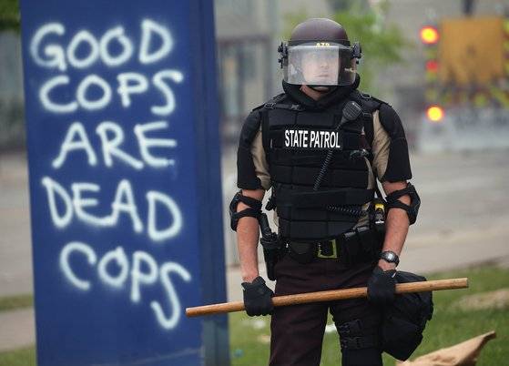 미국 미네소타주 미니야폴리스에서 시위 집압에 동원된 경찰 옆에 '좋은 경찰은 죽은 경찰밖에 없다'는 낙서가 적혀 있다. '좋은 인디언은 죽은 인디언밖에 없다'는 서부 개척시대 백인들의 차별적인 말을 비꼬아 경찰에 대한 분노를 나타냈다. AFP=연합뉴스,