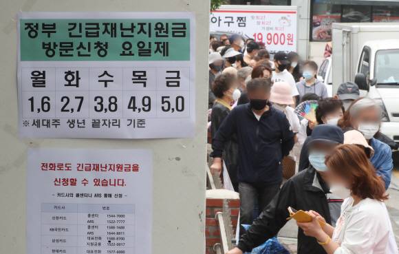 기본소득 도입이 정치권 화두로 떠오르고 이재명 경기지사가 2차 긴급재난지원금을 전 국민에게 지급해야 한다고 정부에 건의한 가운데 앞서 지난달 18일 경기 고양시 주엽1동주민센터에서 시민들이 코로나19 관련 정부 긴급재난지원금 신청을 위해 줄을 서고 있는 모습.뉴스1