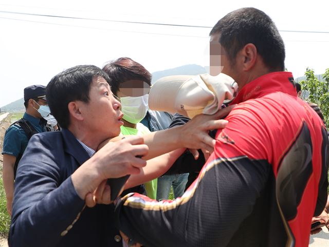 박상학(왼쪽) 자유북한운동연합 대표가 지난 8일 인천 강화군 삼산면 석모리의 해안진입로 통행을 막아선 주민에게 반발하고 있다. 박 대표와 탈북민단체 회원들은 쌀을 담은 페트병을 바다에 띄워 북한에 보내려 했지만 주민들의 제지에 부딪혀 실패했다. 연합뉴스