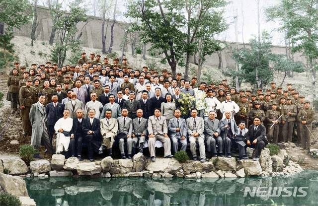 [서울=뉴시스] 1948년 4월 25일 오후 남북제정당·사회단체연석회의 개최 축하 공연을 마치고 주요 간부들과 조선인민군협주단원들이 북조선인민회의 청사 후원에서 기념 촬영을 하고 있다. 1열 왼쪽 세 번째 부터 허헌 남조선노동당 위원장, 김원봉 조선인민공화당 위원장, 이극로 민족자주연맹 정치위원, 김두봉 북조선인민위원회 부위원장, 김일성 북조선인민위원회 위원장, 박헌영 남조선노동당 부위원장 등의 모습이 보인다. 사진 가운데 군복 입은 사람이 정율성 조선인민군협주단장이다.  사진은 북한이 흑색 사진을 컬러사진으로 변환해 공개한 것이다. (사진=미디어한국학 제공) 2020.06.14. photo@newsis.com