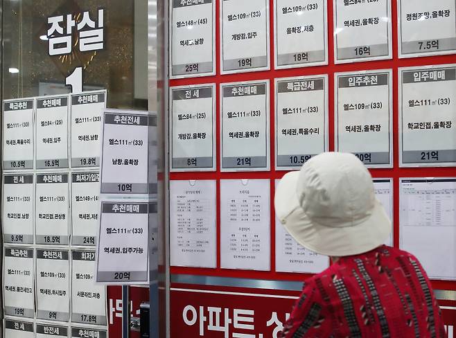 21일 토지거래허가구역으로 지정된 서울 송파구 잠실의 한 부동산 중개업소 앞에서 시민이 매물을 살펴보고 있다. [연합]