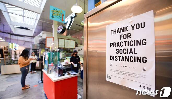 24일(현지시간) 미 캘리포니아 LA 다운타운에 있는 한 상점에 '사회적 거리두기' 안내문이 붙어 있다.© AFP=뉴스1