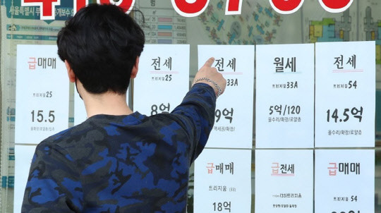한 시민이 부동산공인중개업소에 걸린 아파트 급매물 시세를 가리키고 있다.<연합뉴스>