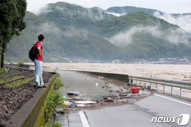 지난 4일 일본 구마모토 현 야쓰시로에서 한 남성이 폭우로 인해 범람한 쿠마강을 바라보고 있다.  © AFP=뉴스1 © News1 이동원 기자