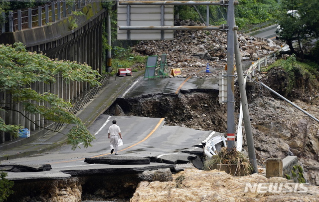 [구마무라=AP/뉴시스]기록적인 폭우가 쏟아진 일본 규슈 지역 구마모토현 구마무라에서 6일 한 남성이 파손된  도로 위를 걷고 있다. 2020.07.07.