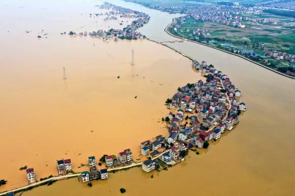 중국 장시성 주장에서 폭우로 하천 댐이 무너지면서 13일 도로와 건물들이 물에 잠겼다.AFP 연합뉴스