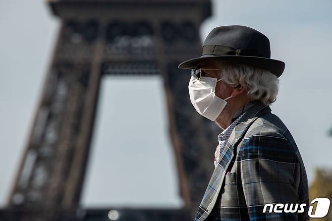 마스크를 착용한 노인이 프랑스 에펠탑을 앞을 지나쳐 걸어가고 있다. © AFP=뉴스1