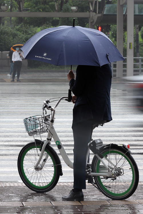 7월 들어 폭염 대신 선선한 날씨가 나타나고 있는 가운데 20일 서울 여의도 환승센터에서 긴팔 옷을 입은 시민들이 우산을 쓰고 출근하고 있다.  뉴시스