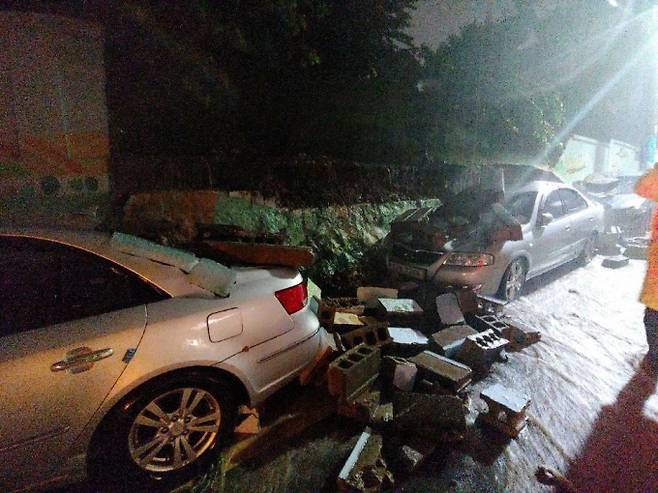 ▲ 23일 밤 부산 중구 배수지 체육공원 2m 높이의 담벼락 상단 블록이 넘어져 주차돼 있던 차량 4대가 파손돼 있다.(사진= 부산소방재난본부 제공)