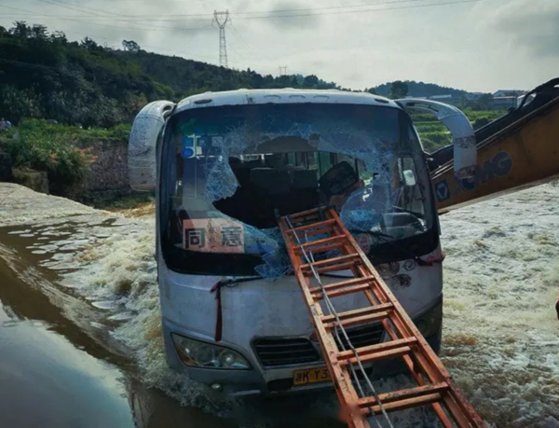 갑자기 불어난 강물에 떠내려갈뻔한 버스를 굴착기가 기중기 팔을 뻗어 지탱해주자 소방대원들이 버스 앞 유리창을 깨고 사다리를 연결해 구조 작업을 펼칠 수 있었다. [중국 인민망 캡처]