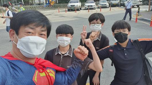 슈퍼맨 복장을 한 강정훈 교사가 아이들과 사진을 찍고 있다.(사진=강정훈교사)