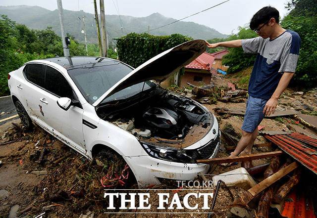 3일 오전 산사태가 발생한 경기 안성시 금일로의 한 주택가에서 주민이 토사에 파묻힌 차량을 살펴보고 있다. /안성=이덕인 기자