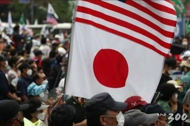 개신교발 코로나19 확진자가 폭증하고 있는 가운데 15일 오후 서울 광화문 세종대로 일대에서 열린 보수단체의 문재인 정부 규탄 대규모 집회에서 한 집회 참석자가 태극기와 성조기, 일장기를 들고 있다./온라인커뮤니티