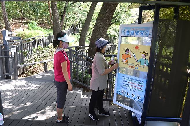 지난 18일 서울 노원구 영축산 무장애숲길 산책로에 마련된 힐링냉장고에서 주민들이 생수병을 꺼내고 있다.2020.8.21. 노원구 제공