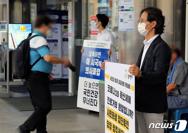 2일 오전 서울 종로구 서울대병원 본관 앞에서 한 전공의가 정부의 의료정책을 반대하는 내용이 적힌 피켓을 들고 있다. 앞쪽으로는 윤홍식 참여연대 사회복지위원장이 의사협회의 진료거부 철회 촉구 1인 시위를 하고 있다. 2020.9.2/뉴스1 © News1 이재명 기자