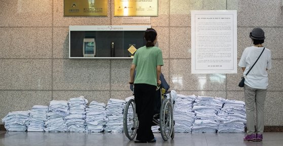 지난달 23일 서울 송파구 서울아산병원 로비에서 환자와 보호자들이 전공의들이 벗어놓은 의사 가운 위로 붙은 입장문을 바라보고 있다. 뉴스1