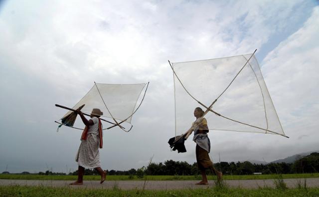 인도 아삼주 가우하티 외곽에서 26일 여성들이 낚시를 하기 위해 그물을 옮기고 있다. 가우하티=EPA 연합뉴스