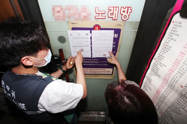 8월 20일 서울 성동구청 문화체육과 직원들이 고위험시설로 분류된 관내 노래방에 집합금지명령서를 붙이고 있다. 뉴시스