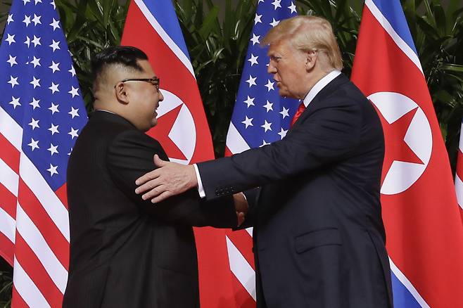 North Korean leader Kim Jong-un (left) shake hands with US President Donald Trump at summit in Singapore on June 12, 2018. (AP-Yonhap)