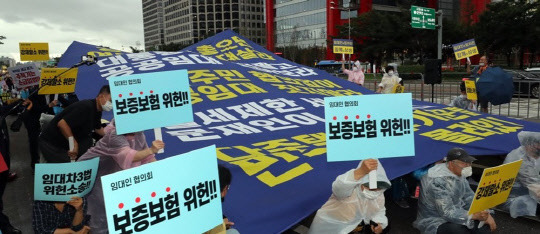 정부의 부동산 규제 정책에 반대하는 시민들이 지난 8월 열린 집회에서 임대차3법 등에 반대하는 구호를 외치며 대형 현수막을 펼치고 있다. <연합뉴스>