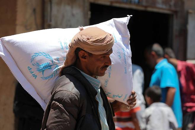 지난 10일 예멘에서 세번째로 큰 도시인 타에즈에서 한 남성이 WFP로부터 지원받은 식량을 들고 가는 모습. WFP는 코로나19 상황에서 기아 해소와 식량 공급에 기여한 공로로 올해의 노벨평화상 수상자로 선정됐다. AFP=연합뉴스