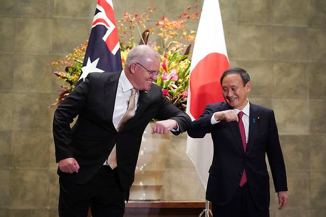 스콧 모리슨(왼쪽) 호주 총리와 스가 요시히데 일본 총리가 17일 일본 도쿄의 총리 관저에서 팔꿈치 인사를 하고 있다. 두 사람은 중국의 세력 확대에 맞서 협력을 강화하기로 했다./AP 연합뉴스