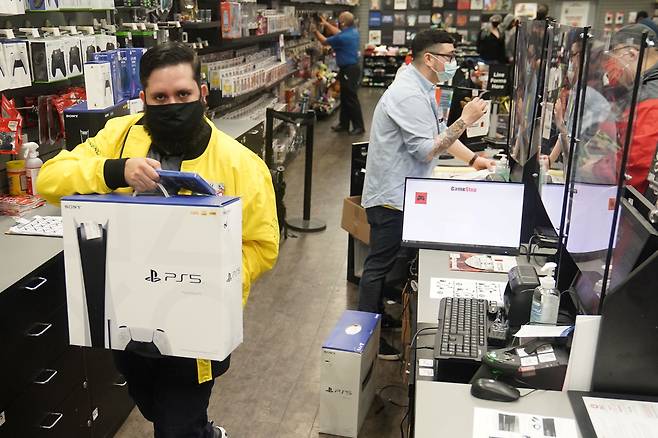 지난 12일 미국 뉴욕 맨해튼의 게임스톱 가게에서 직원이 플레이스테이션 5 신상품을 들고 이동하고 있다.