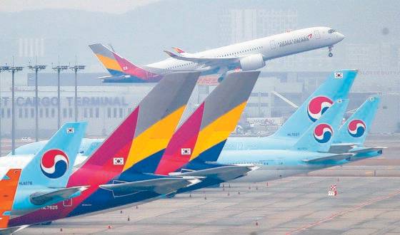 18일 인천국제공항 주기장에 세워진 대한항공과 아시아나항공 여객기 뒤로 아시아나항공 여객기가 이륙하고 있다. 연합뉴스