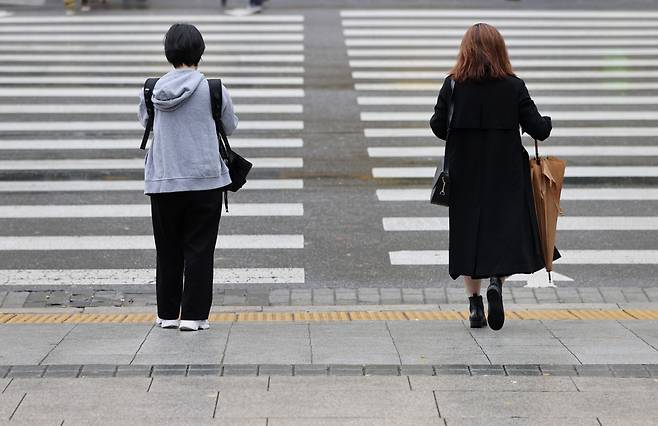 Passersby stand in distance as they wait to cross a road at Gwanghwamun in Seoul. (Yonhap)