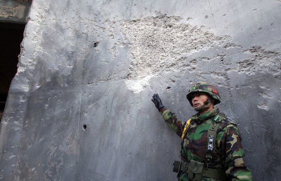 2010년 북한군의 포격 도발 당시 포탄을 맞은 연평도 자주포 진지 흔적을 한 해병대 장교가 설명하고 있다. [사진공동취재단]