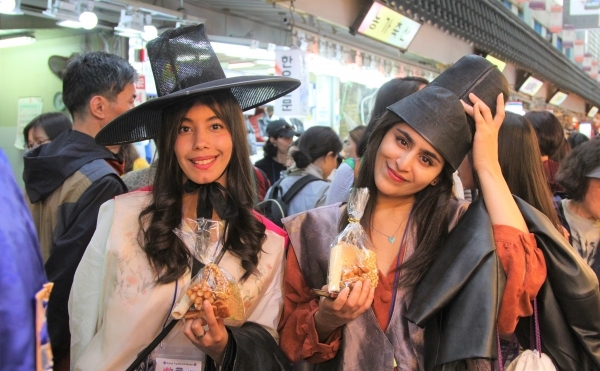 Foreigners, wearing traditional costumes of the Joseon Dynasty (1392-1910), pose with Korean traditional cookies at Nammun Market in Suwon, Gyeonggi Province in May 2019. (Korea Tourism Organization)