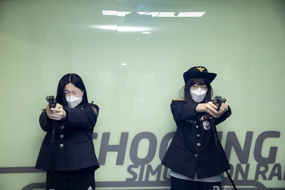 시뮬레이션 사격게임에 참여한 한서진(왼쪽)·박지민 학생기자. 사격 체험에 사용되는 3.8 구경 권총은 안전을 위해 발사 장치를 제거했다.