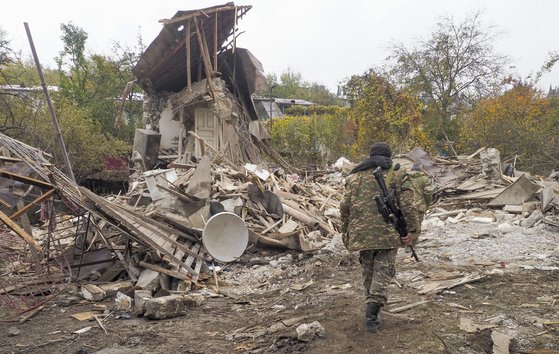 아르메니아군 병사가 아제르바이잔 포격으로 파괴된 민가 옆을 지나고 있다. [AP=연합]