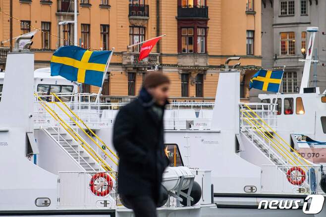 3일 스웨덴 스톡홀름의 통근용 페리. 그 앞에선 마스크를 쓰지 않은 행인이 걷고 있다. © AFP=뉴스1