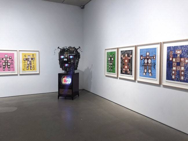  TV모니터 세 대와 다양한 오브제로 인간형상을 만든 ‘볼타’와 다양한 판화작품. 리안갤러리 서울 전시전경.[리안갤러리·헤럴드DB]