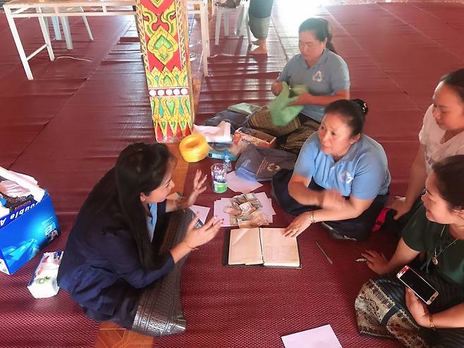 An official from the Lao government teaches members of Saemaul Geumgo in Phonhong district, Vientiane Province on how to write account books. (Korean Federation of Community Credit Cooperatives)