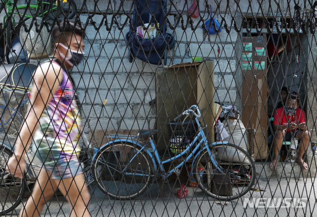 [마닐라=AP/뉴시스]7월16일(현지시간) 신종 코로나바이러스 감염증(코로나19) 확진자 증가로 필리핀 마닐라 나보타스시에 봉쇄가 시작된 가운데 마스크를 착용한 한 주민이 그 앞을 지나고 있다.  2020.07.16.